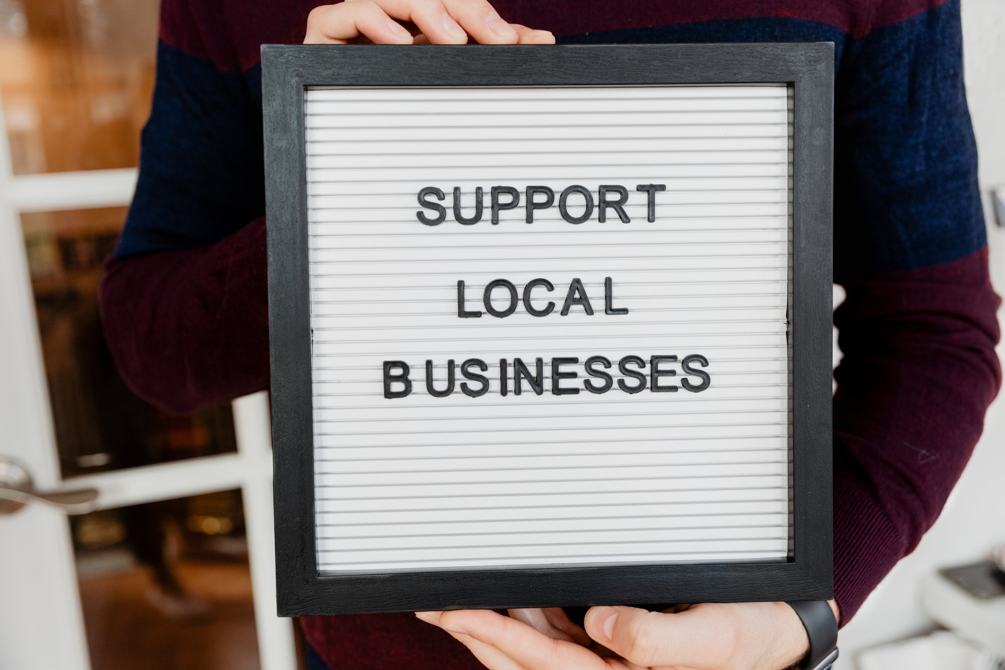 Sign being held that says support local business